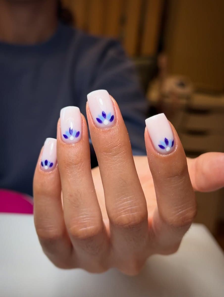 A neutral manicure with delicate blue floral accents.