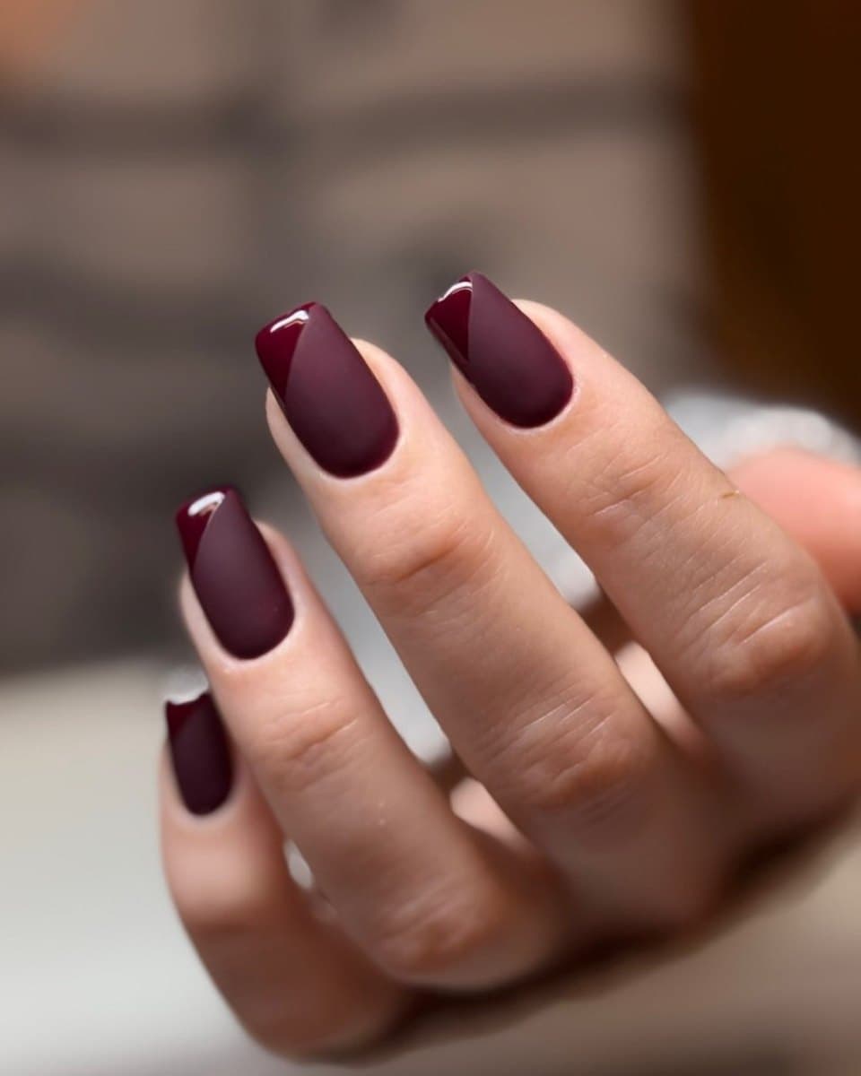Long almond nails in a deep burgundy tone.